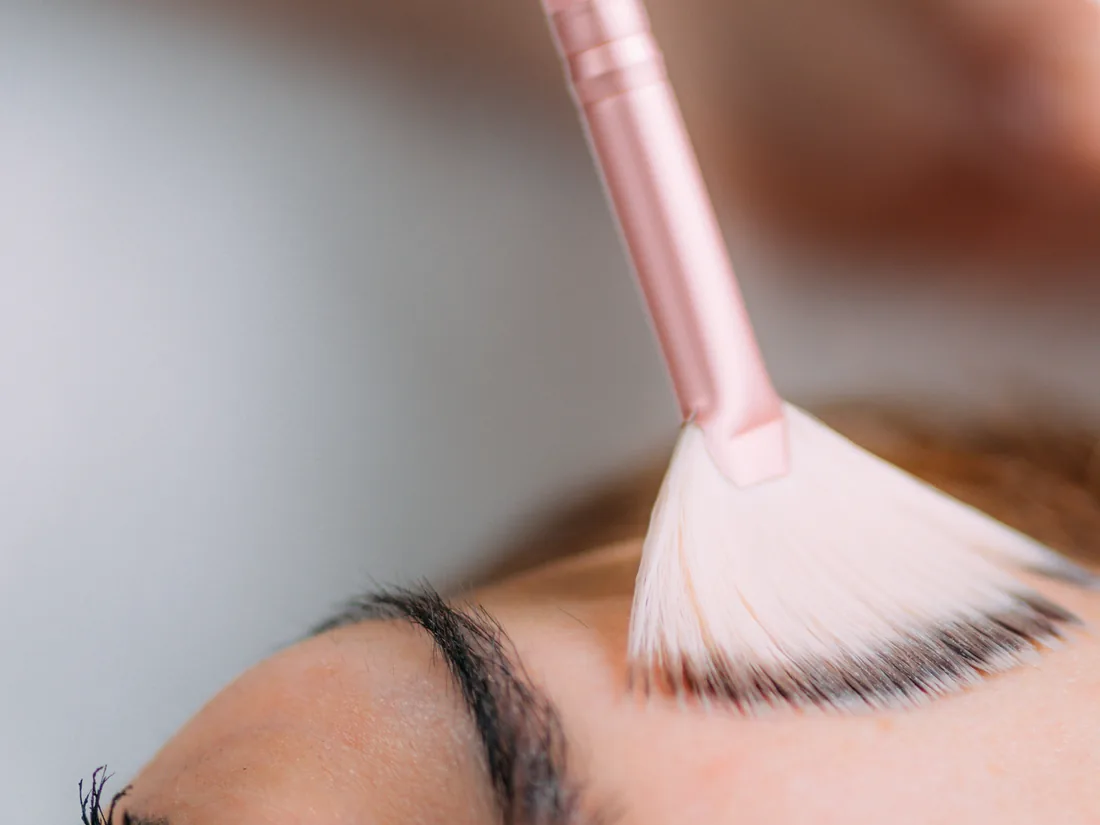 Chemical peel being applied to the face with a fan brush to brighten dull skin